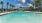 a swimming pool with chairs and a building in the background