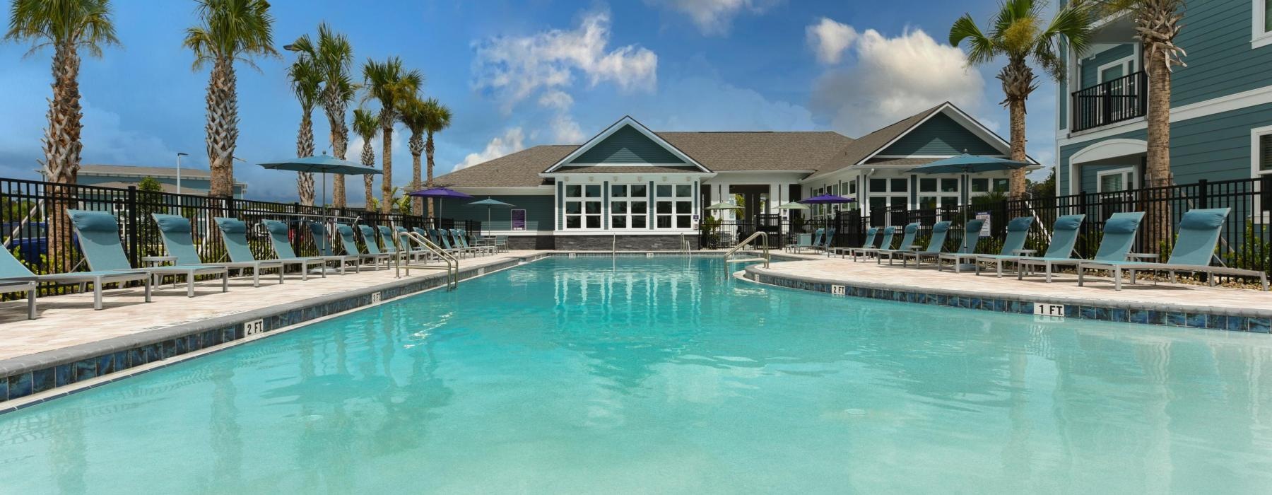 a swimming pool with chairs and a building in the background